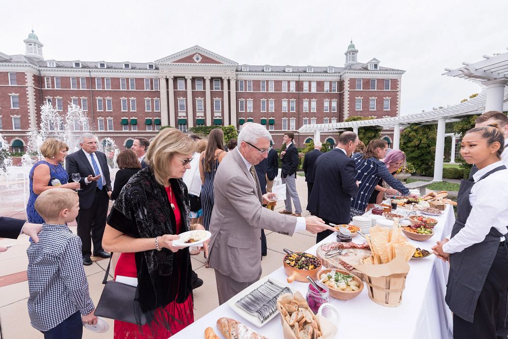 Guests line up at a catered table of meats, breads, and salads to serve themselves on CIA's Hyde Park, NY campus.