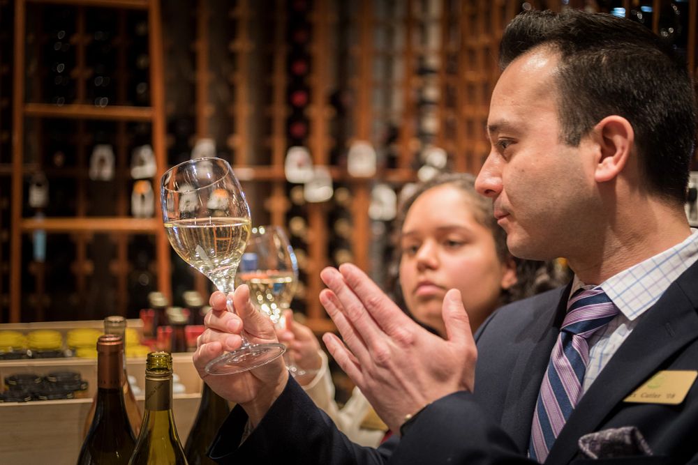 Two CIA staff members study glasses of white wine in American Bounty's wine room at the New York campus.