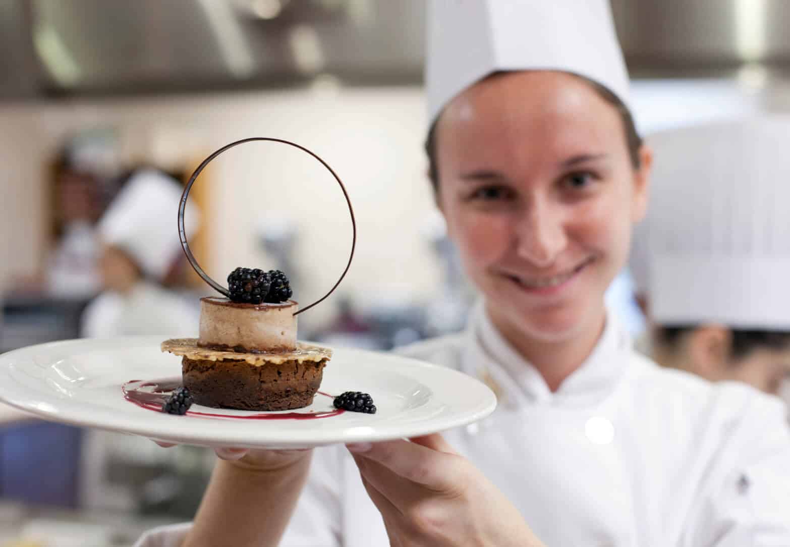 A CIA Greystone baking & pastry arts student holding up a beautiful dessert.