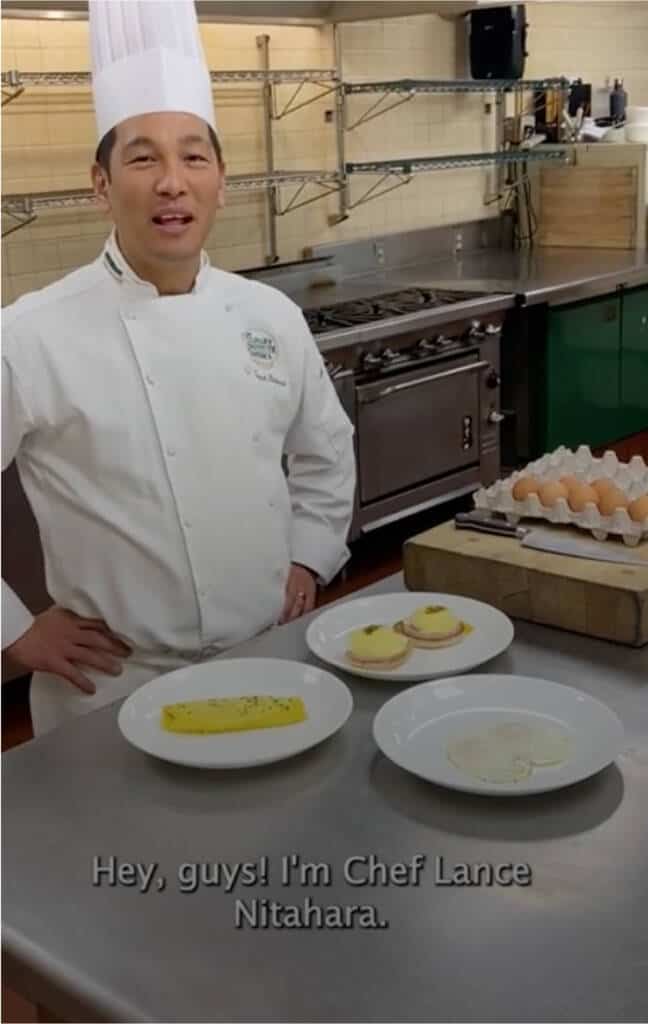 A chef in a white chef's coat and hat stands in a kitchen behind a counter with three plates of food and a tray of eggs. The text overlay reads, "Hey, guys! I'm Chef Lance Nitahara.