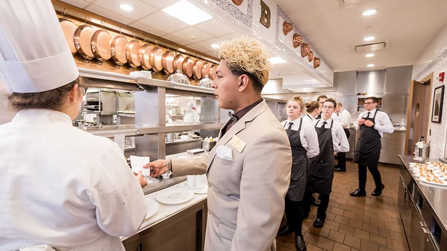 CIA students working in a restaurant kitchen for lunch service.
