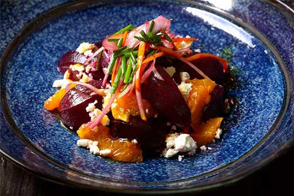 Image of a roasted beets with feta and tangerines salad in a blue bowl.
