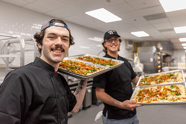 Image of two CIA students competing in the 2025 Pizza Cook-Off at the Hyde Park, NY campus.