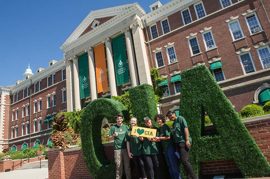 Image of CIA students standing in front of a big CIA green sign outside Roth Hall.