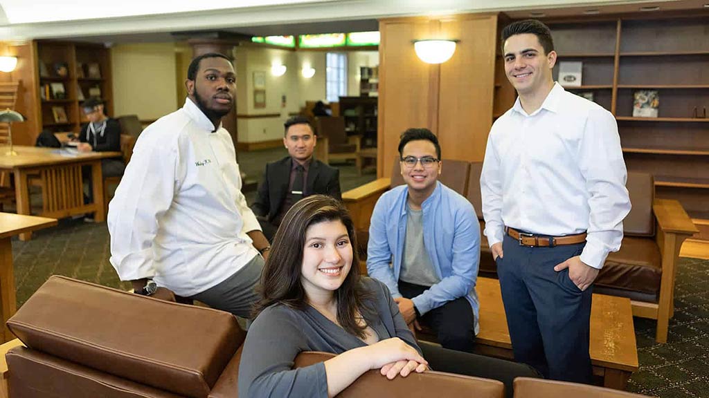Image of smiling CIA international students sitting in a library.