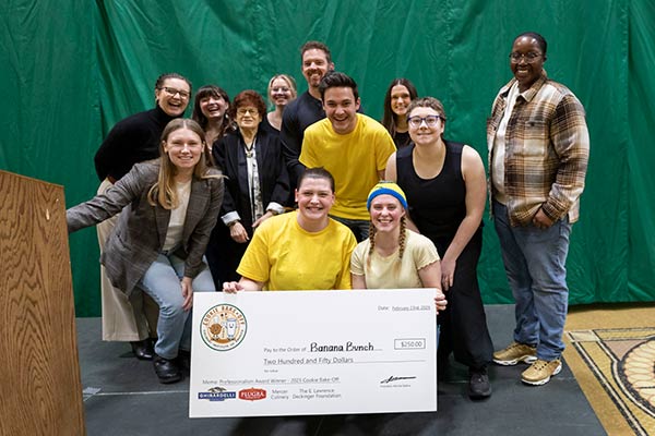 A group of CIA students  with a large $250 check for winning the CIA Cookie Bake Off contest.