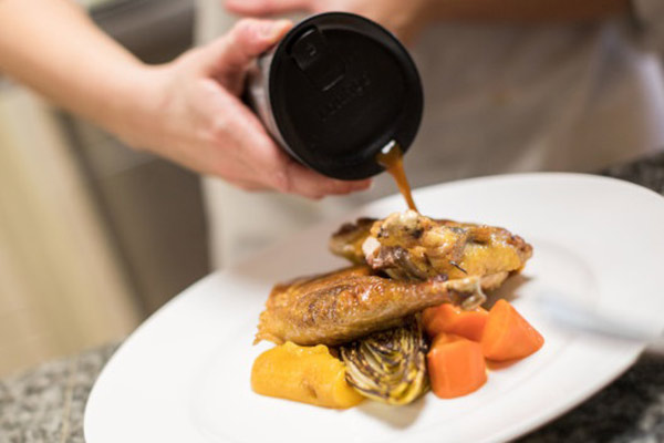 Image of someone pouring a sauce over plated food.