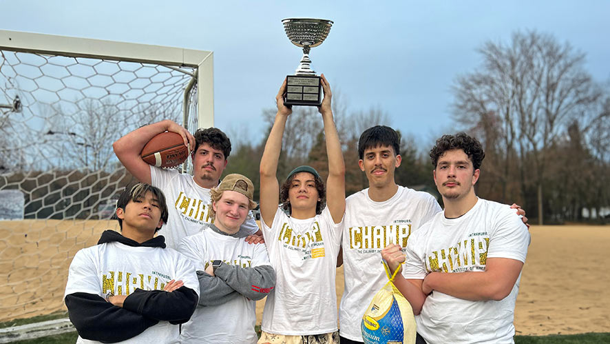 Image of CIA Intramural Football Champions holding up a trophy and wearing championship t-shirts.