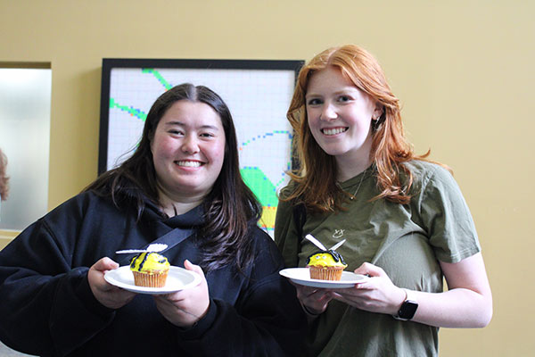 Image of two CIA students with Sting cupcakes, celebrating Pollinator Week.