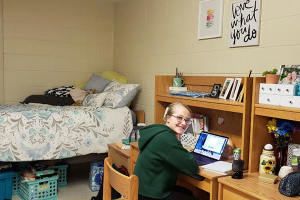 Image of a CIA student sitting at her desk in her dorm room.