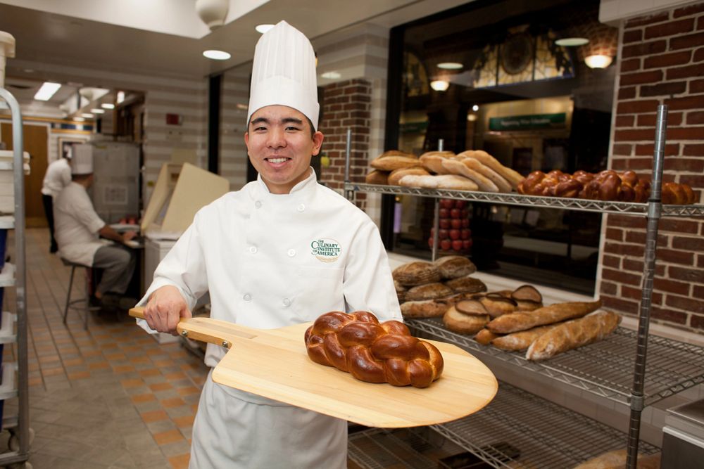 Baking and Pastry student Martin Yeung holds a loaf of challah in the bakeshop of APBC.