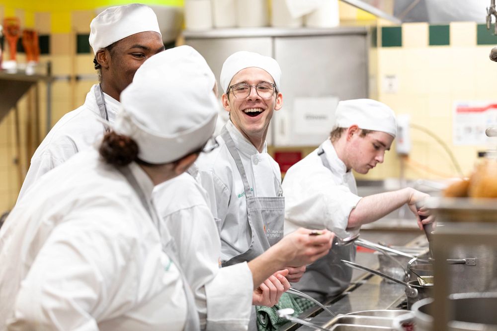 image_tooltip CIA students laugh as they learn confectionary art within the kitchen.
