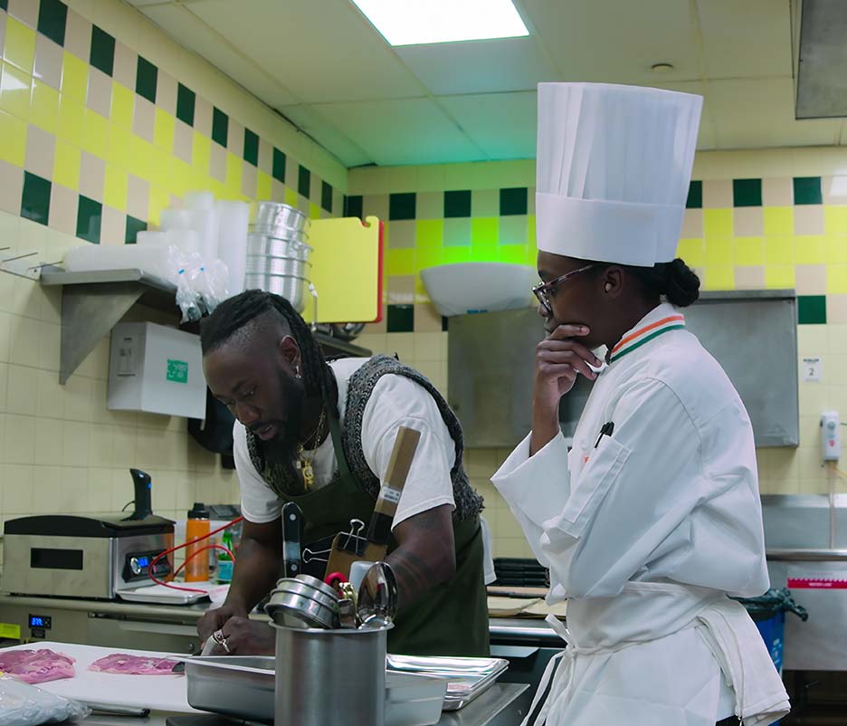 CIA Chef Roshara Sanders observes a chef contestant in a professional kitchen.