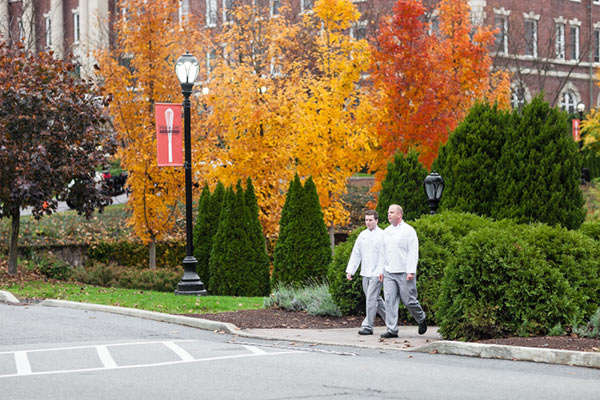 Image of CIA students walking on campus in the fall with yellow, red, brown, and green leaves.