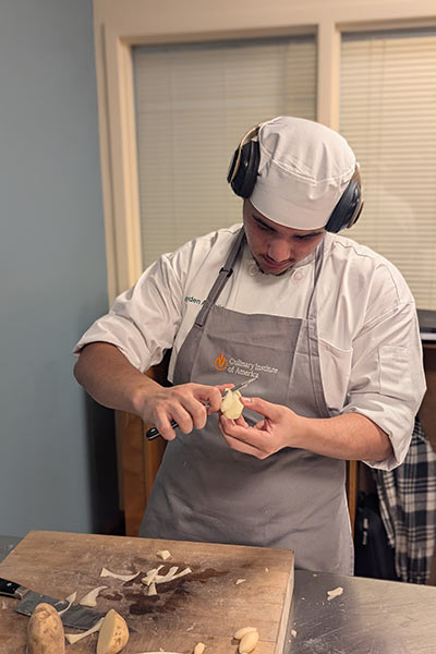 Image of a CIA student practicing his knife skills in The Russell H. Ferber Learning Commons in the Conrad N. Hilton Library at CIA in Hyde Park, NY.