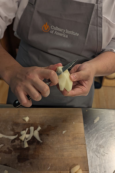Image of a CIA student practicing his knife skills in The Russell H. Ferber Learning Commons in the Conrad N. Hilton Library at CIA in Hyde Park, NY.