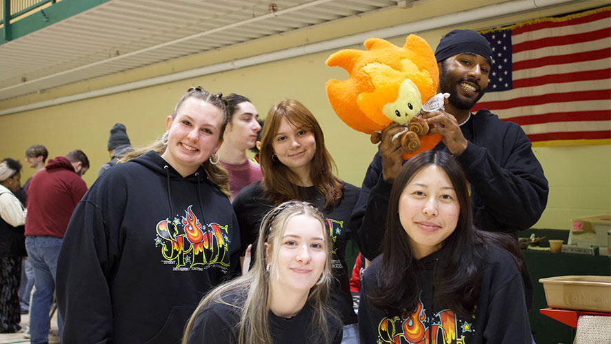 Five CIA students wearing black SPICE hoodies in the gym for CIA Club Con.