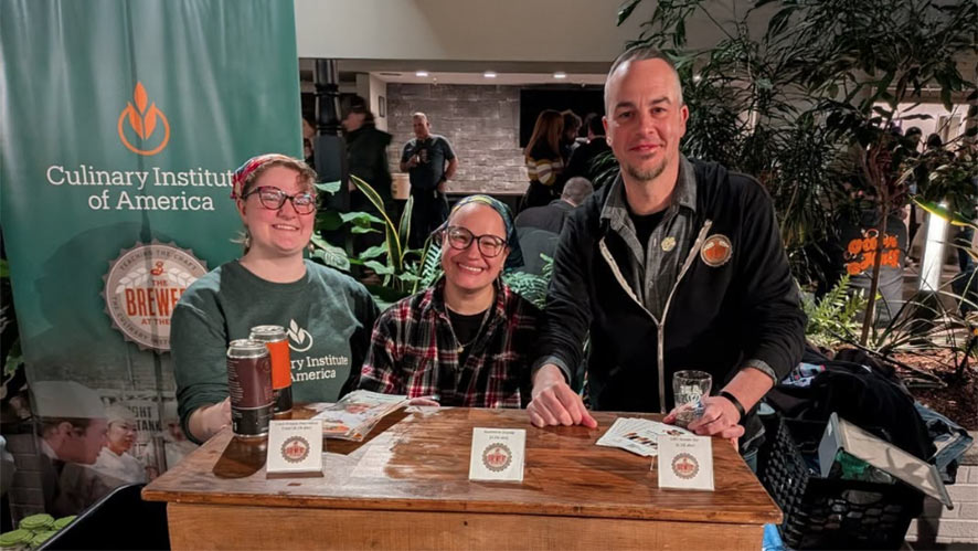 Two CIA students and CIA Head Brewer Hutch Kugeman serving CIA beer at a festival.