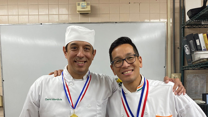 CIA veteran student David Mendiola and CIA Chef Lance Nitahara ’07/’08 take a picture in a kitchen.